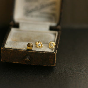 Dainty gold earrings with diamond displayed on a vintage jewellery box